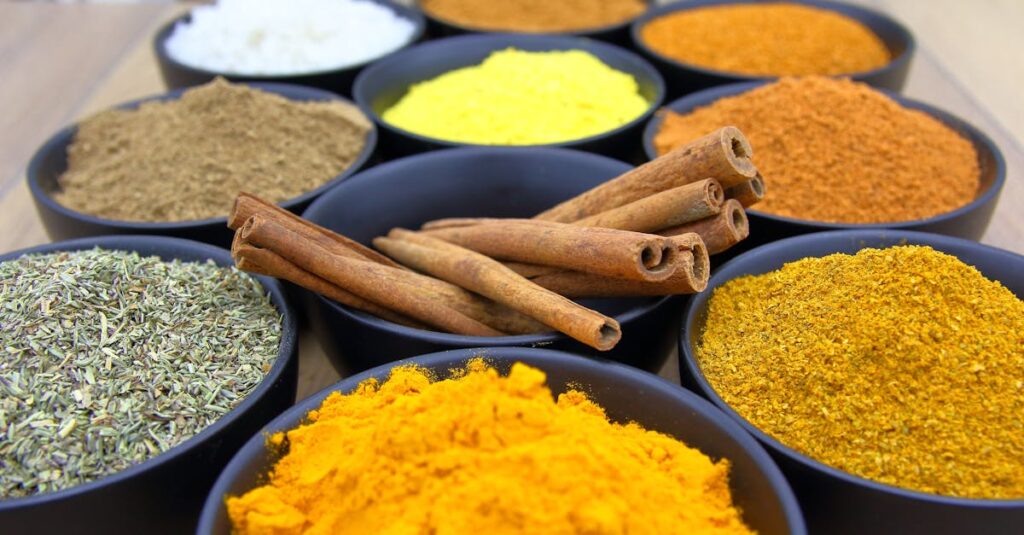 Colorful assortment of spices in bowls with cinnamon sticks on a wooden surface.